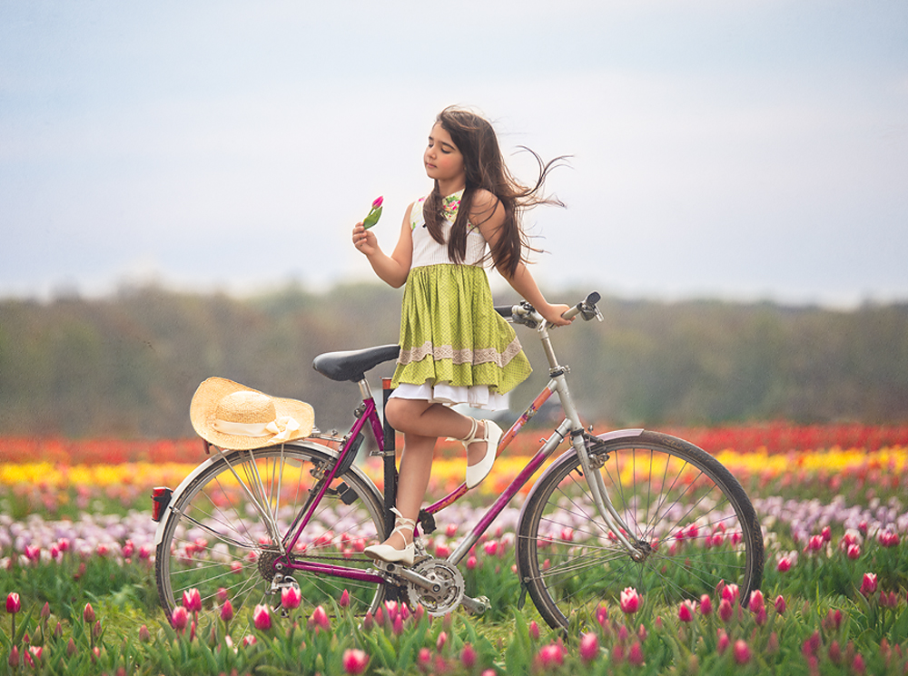 girl on bike in a green dress in a field of tulips Photoshop editing tutorial